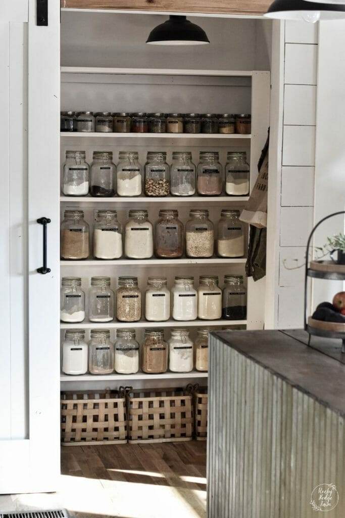 Small, narrow pantry with open wooden shelving and glass jar storage."
Minimalist pantry with glass jars and wooden shelving.