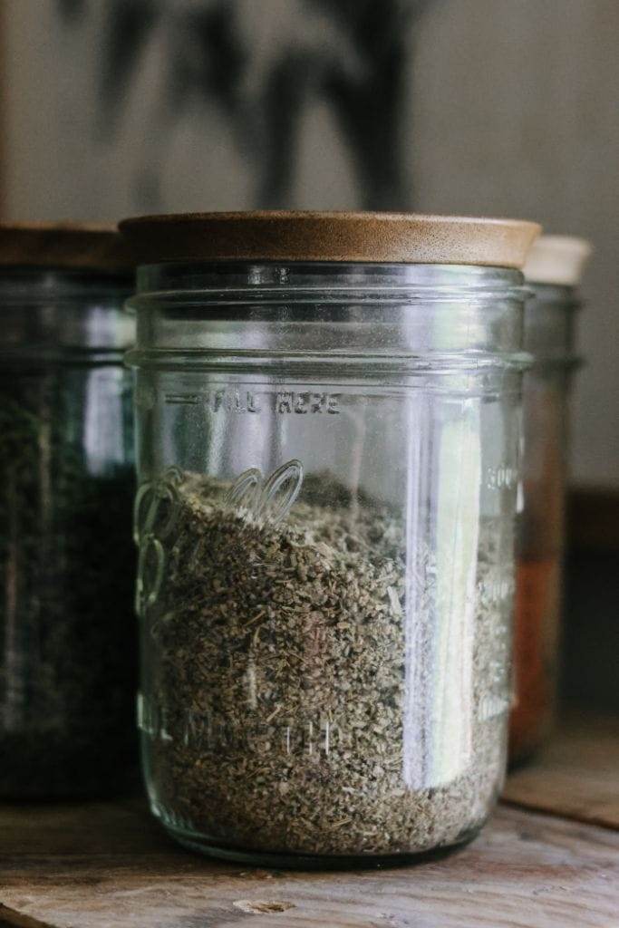 pantry staples of sage in a glass jar with a wooden lid