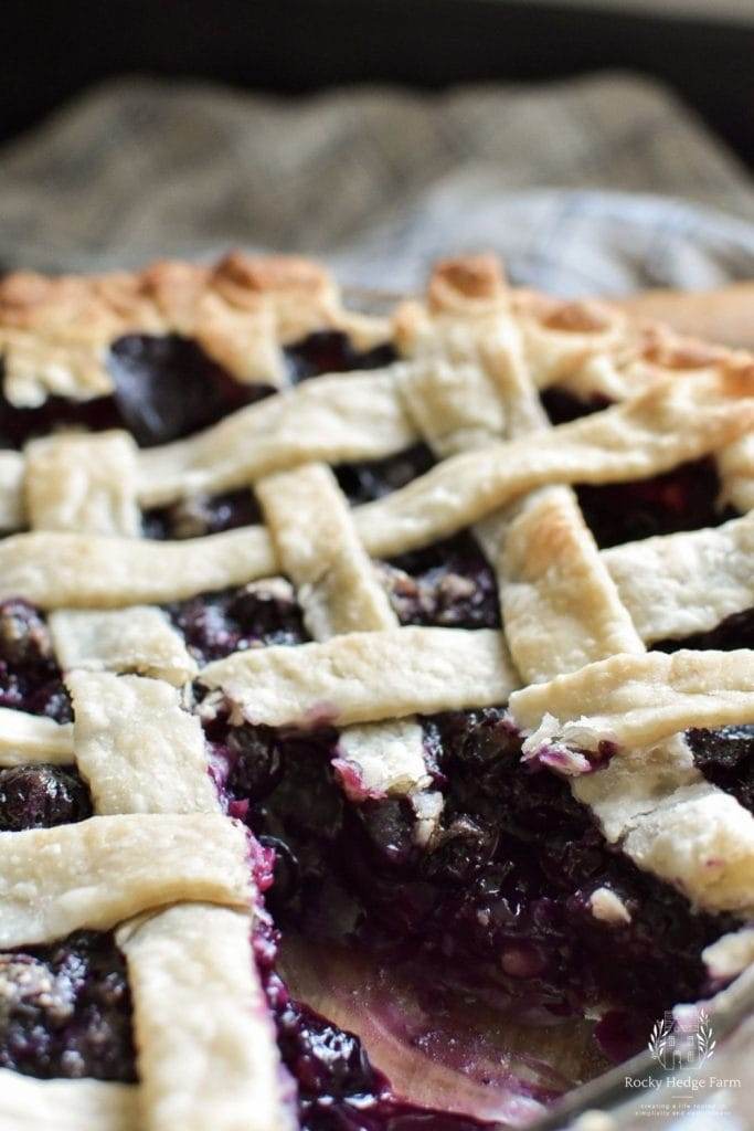 A whole blueberry pie with a slice cut out of it.