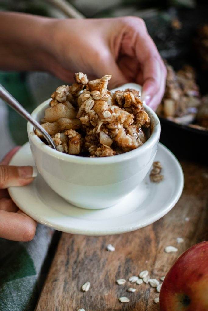 hands holding a bowl of apple crisp