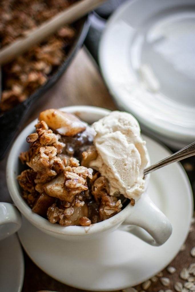 a small bowl with skillet apple crisp topped with vanilla ice cream