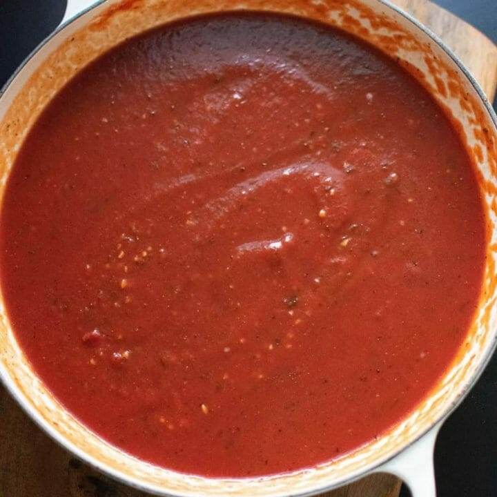 Simmering Italian meatballs sauce on the stovetop in a cast iron skillet.