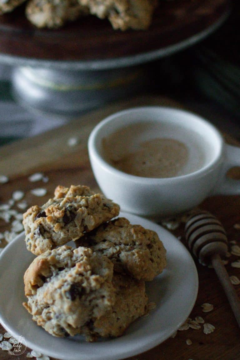 A plate filled with oatmeal and honey cookies along side a hot cup of coffee.