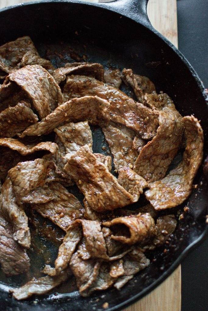 cooked steak fajita strips in a cast iron skillet