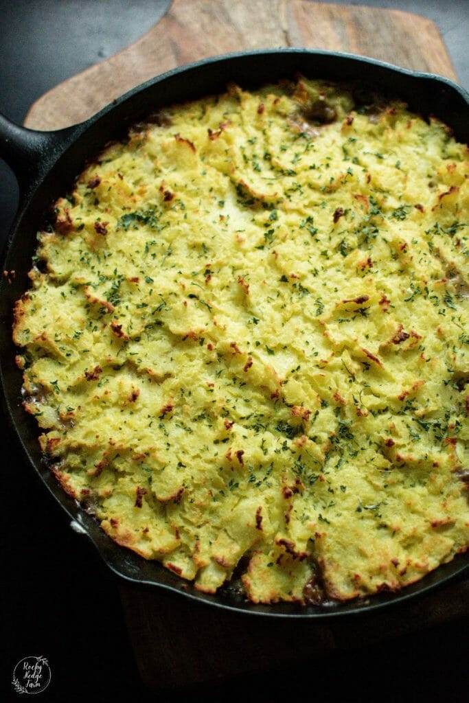 A mouthwatering Shepherd's Pie, with layers of tender ground beef, sweet corn, and fluffy mashed potatoes, served piping hot in a cast iron skillet