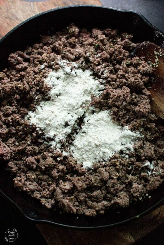 Sprinkled flour on top of the ground beef mixture to make shepherds pie.