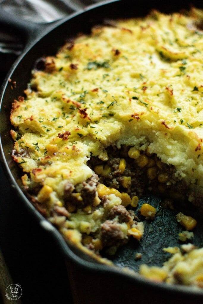 A mouthwatering shepherd's pie in a cast iron skillet, layered with tender ground beef, sweet corn, and a generous serving of creamy mashed potatoes