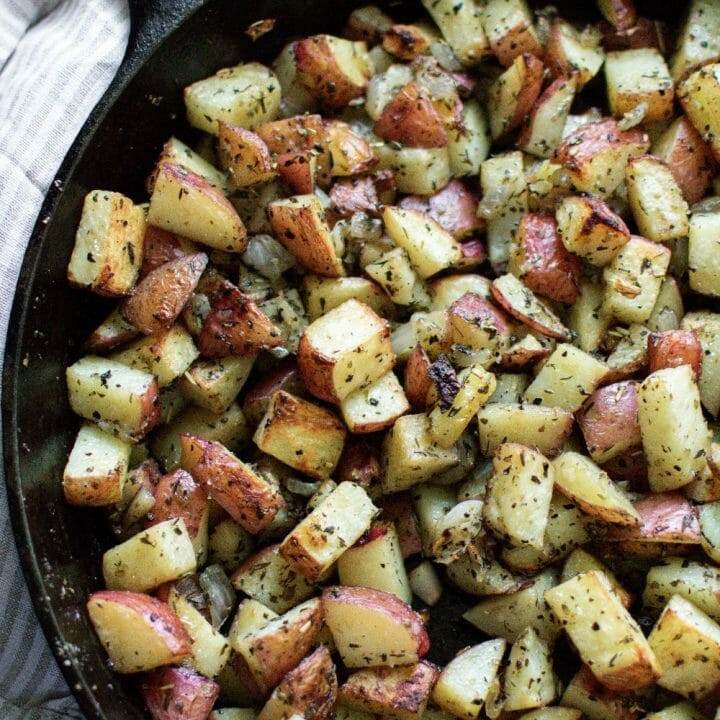 An appetizing sight of roasted potatoes and onions served in a cast iron skillet