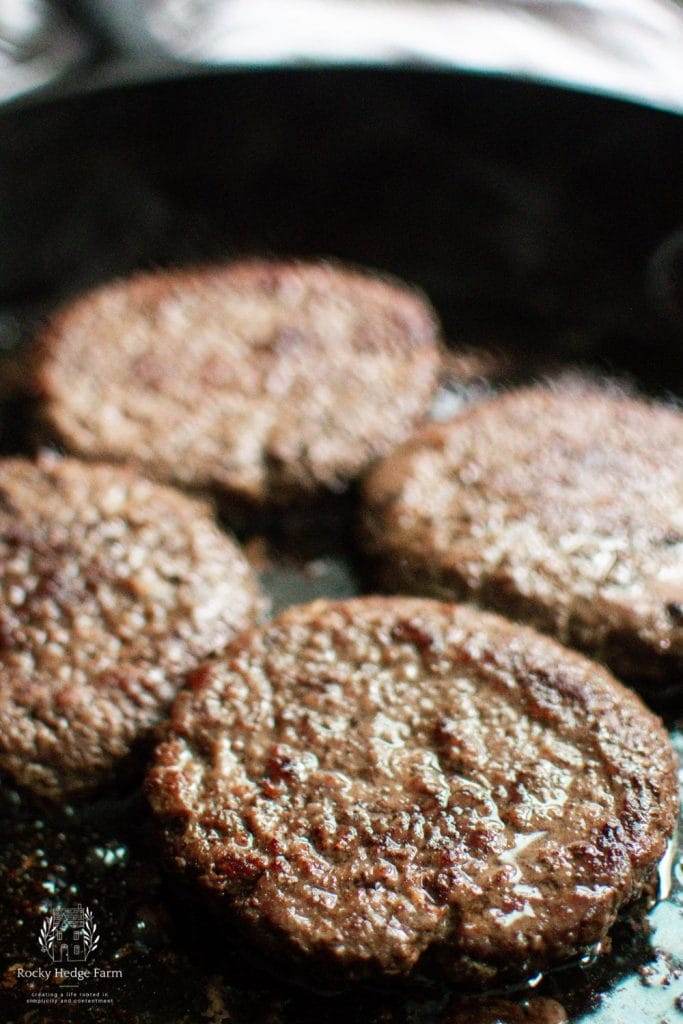 burgers cooking in a cast iron skillet