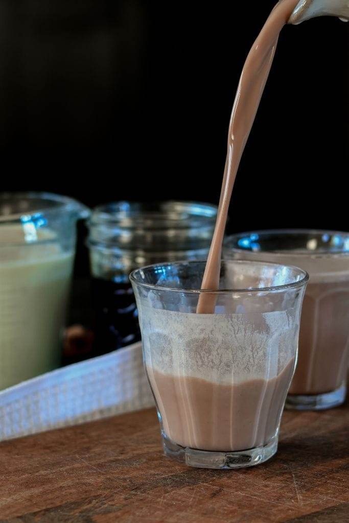 pouring a glass of chocolate milk made with cocoa powder and milk