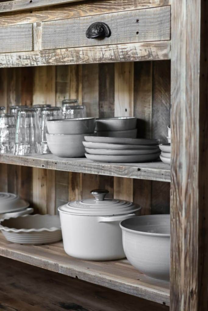 Weathered wood kitchen island with built-in seating for two, optimizing functionality with its shelves and cabinets for additional storage.