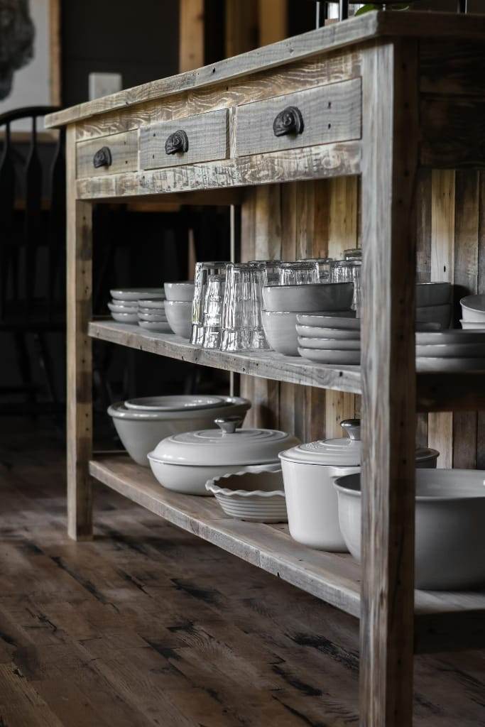 Functional kitchen with a reclaimed wood island, featuring a breakfast bar with two stools and maximizing storage space on the shelves and cabinets.