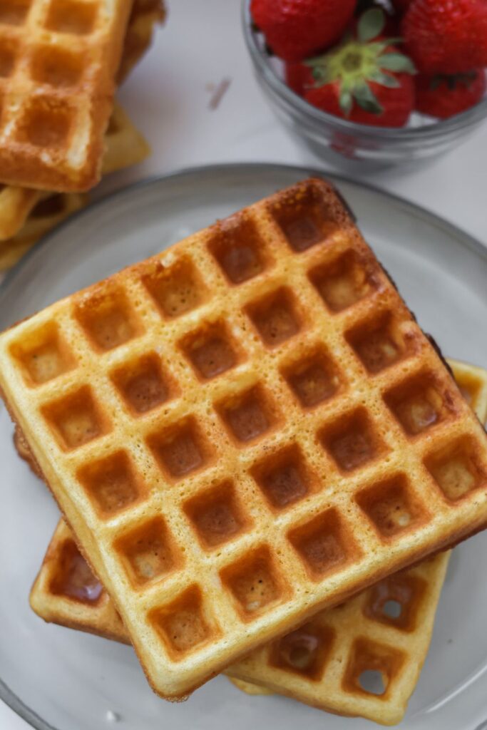 an above view looking down on a stack of waffles with strawberries in the background