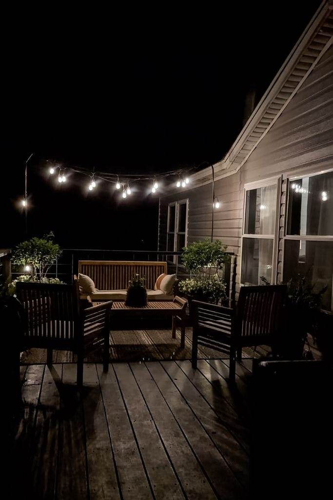 Warm glow of string lights creates a magical atmosphere on this manufactured home porch.