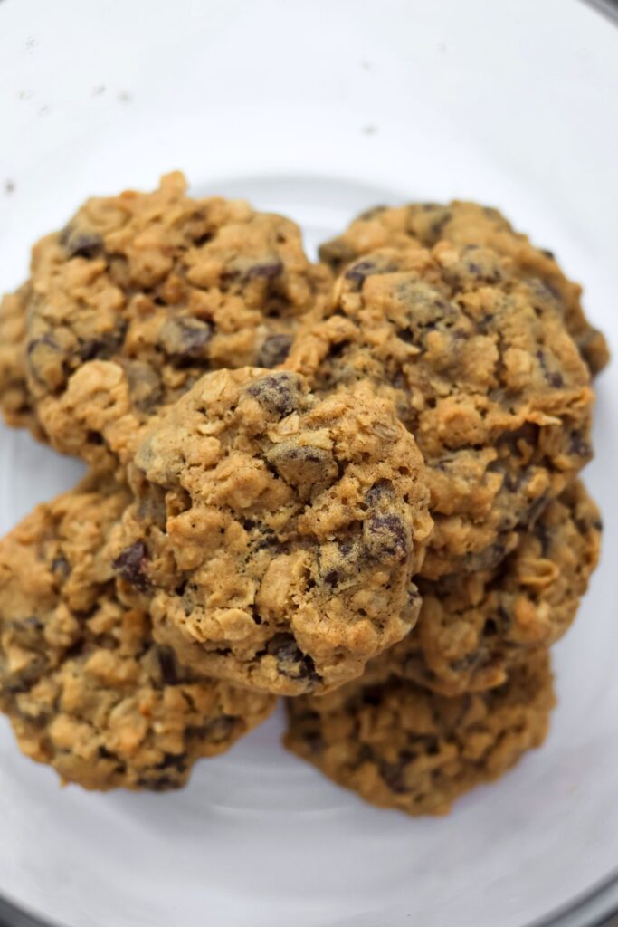 An overhead shot of fully baked no-chill oatmeal chocolate chip cookies in a cookie jar.