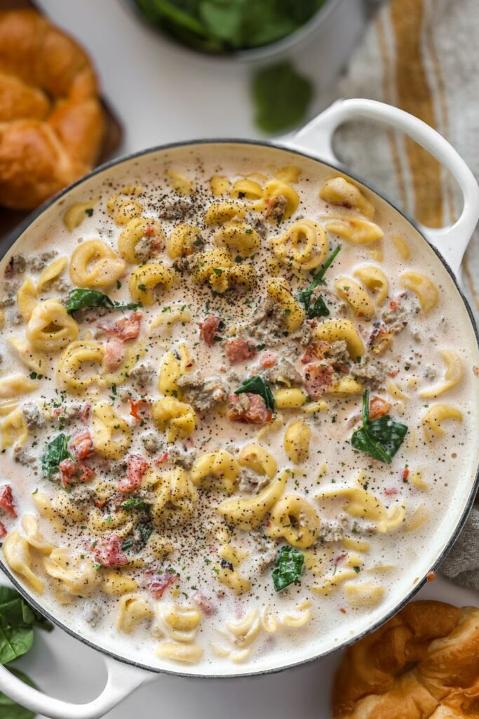 A top-down view of a rustic skillet with steaming tortellini