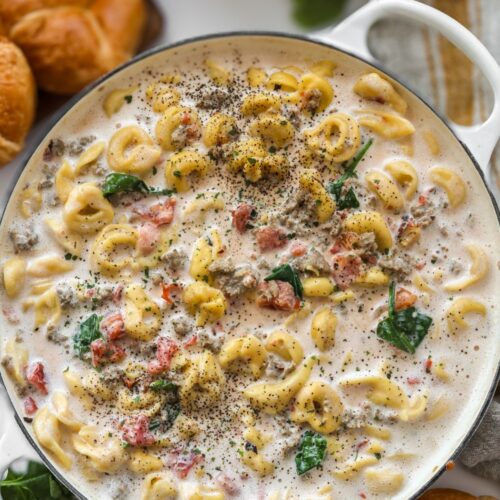 A skillet filled with cheesy tortellini and sausage in a creamy tomato sauce