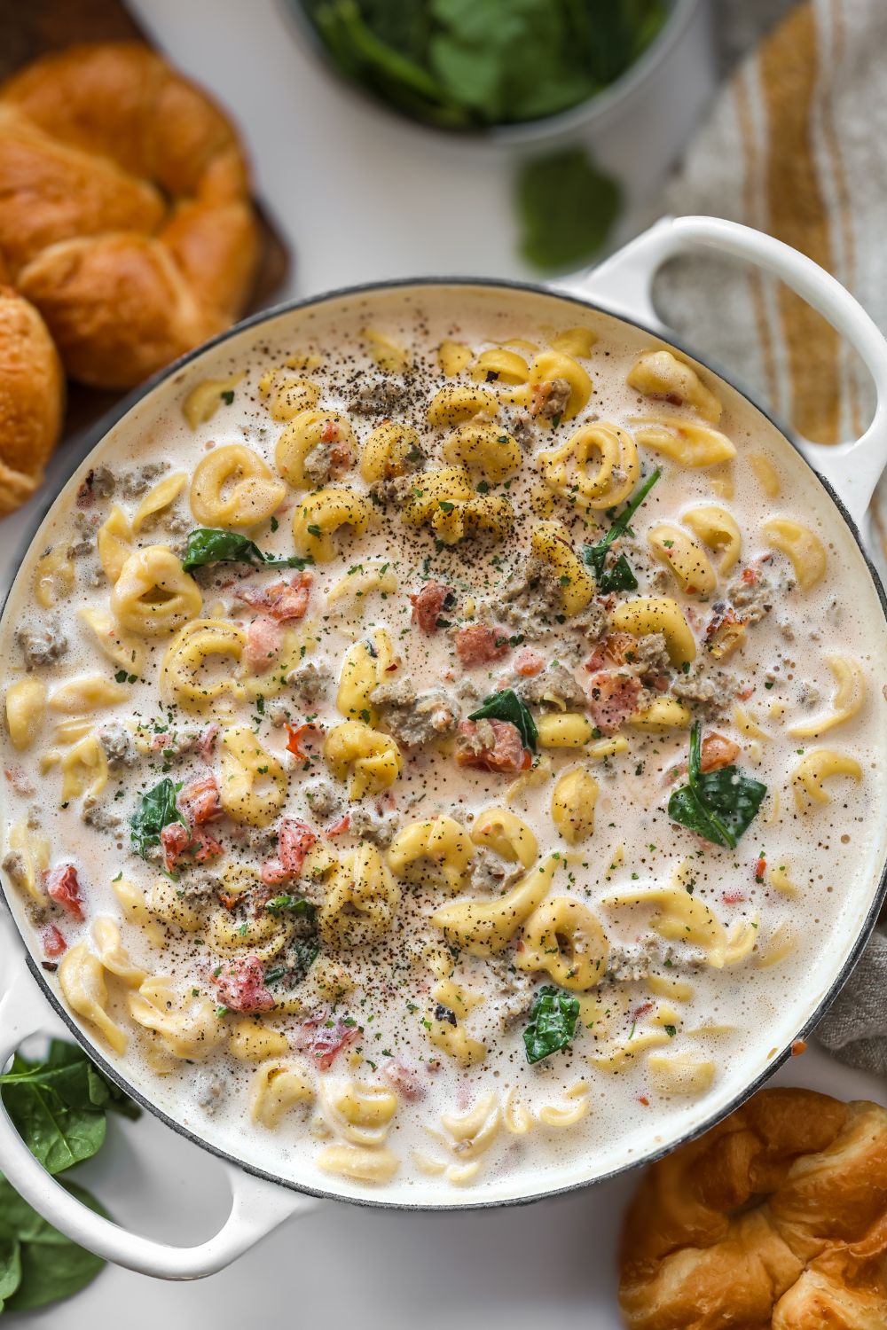 A skillet filled with cheesy tortellini and sausage in a creamy tomato sauce