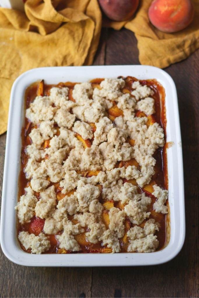 peach cobbler biscuit topping on top of peaches and ready to be baked