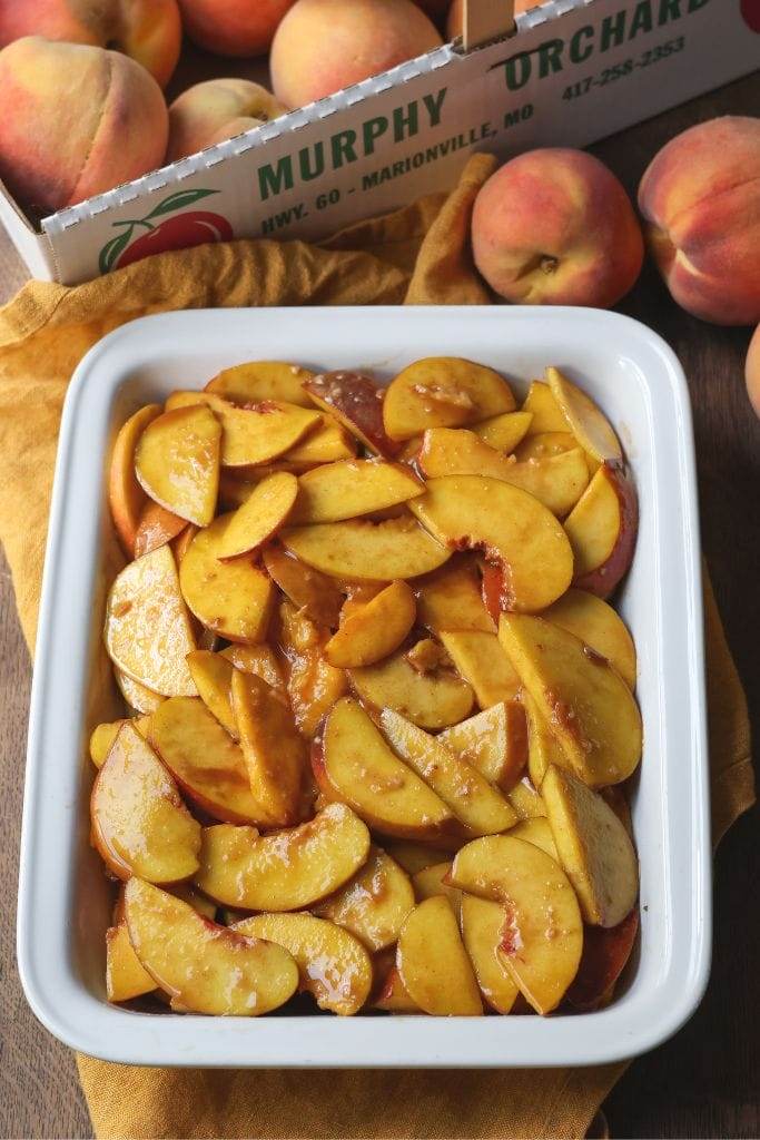 Peaches in a white dish for peach cobbler