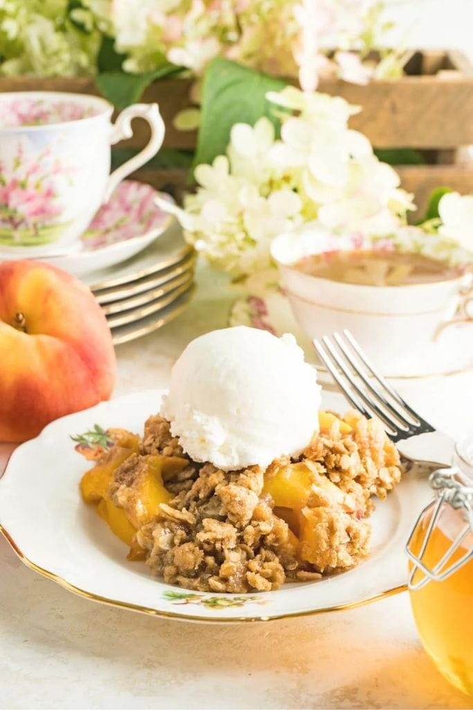 peach crisp on a plate topped with vanilla ice cream