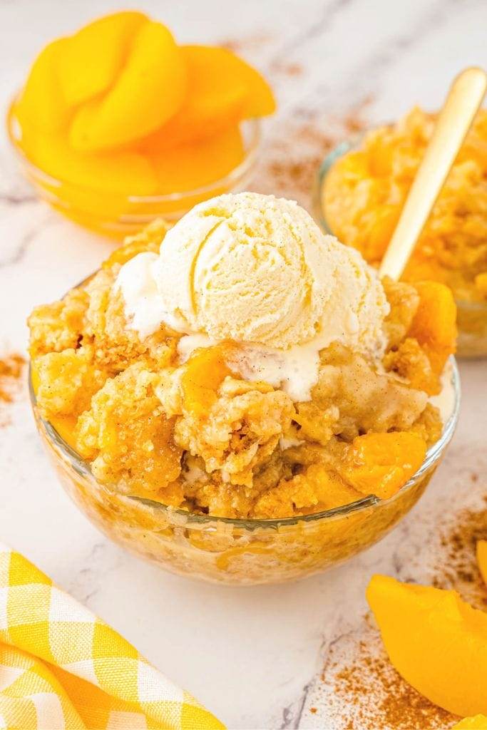 a bowl filled with peach dump cake and topped with vanilla ice cream