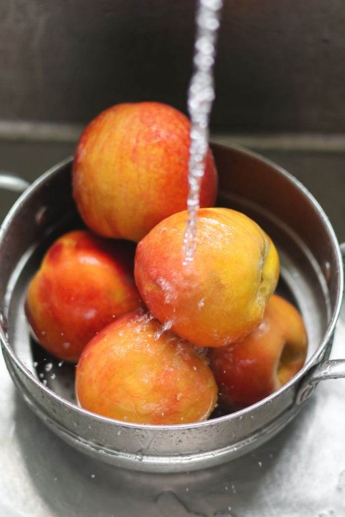 peaches in a colander being washed