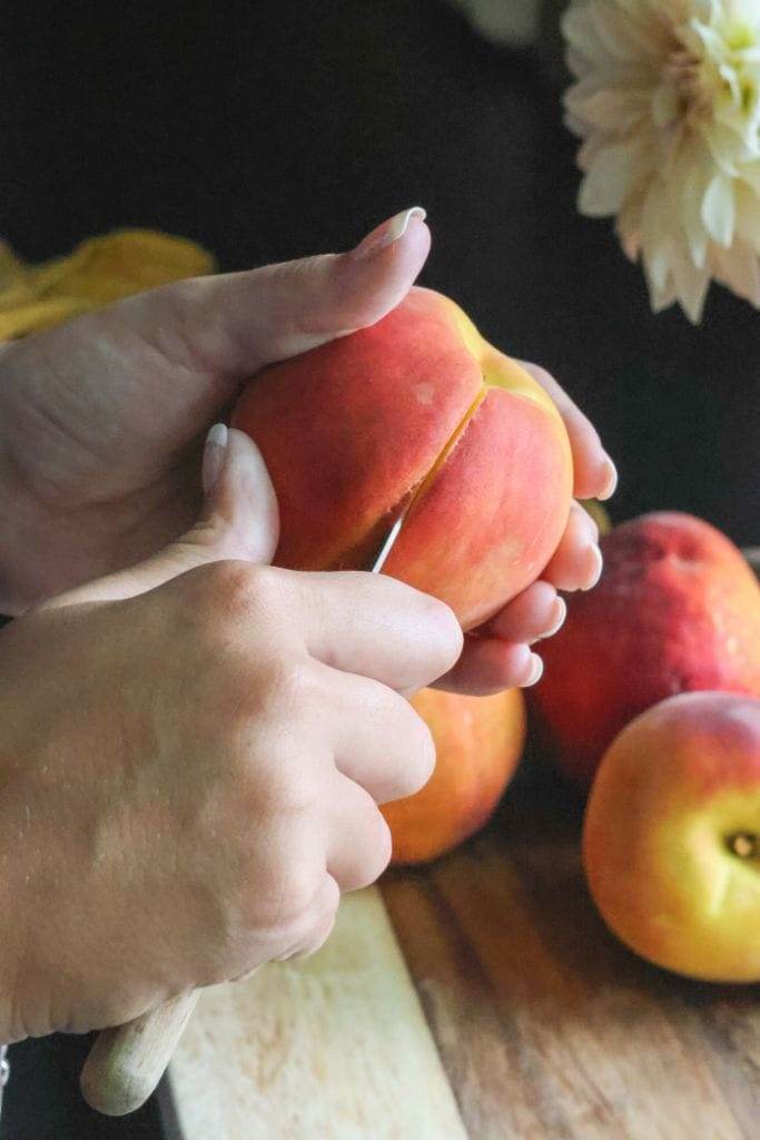 hands cutting a peach