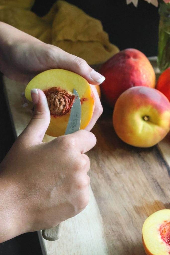 using a knife to remove the pit from the peach