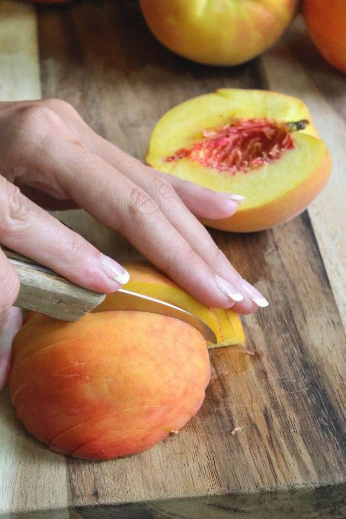 using a knife to slice a peach half