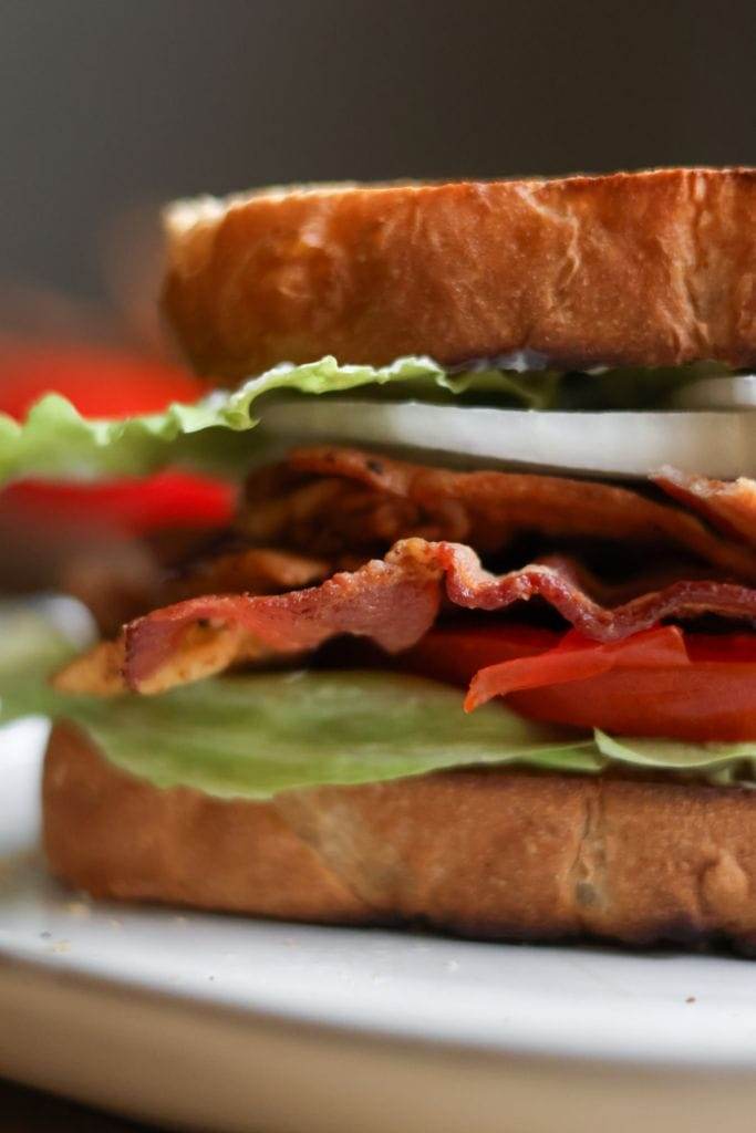 Close-up of a toasted BLT sandwich showing layers of bacon, lettuce, tomatoes, and mayonnaise