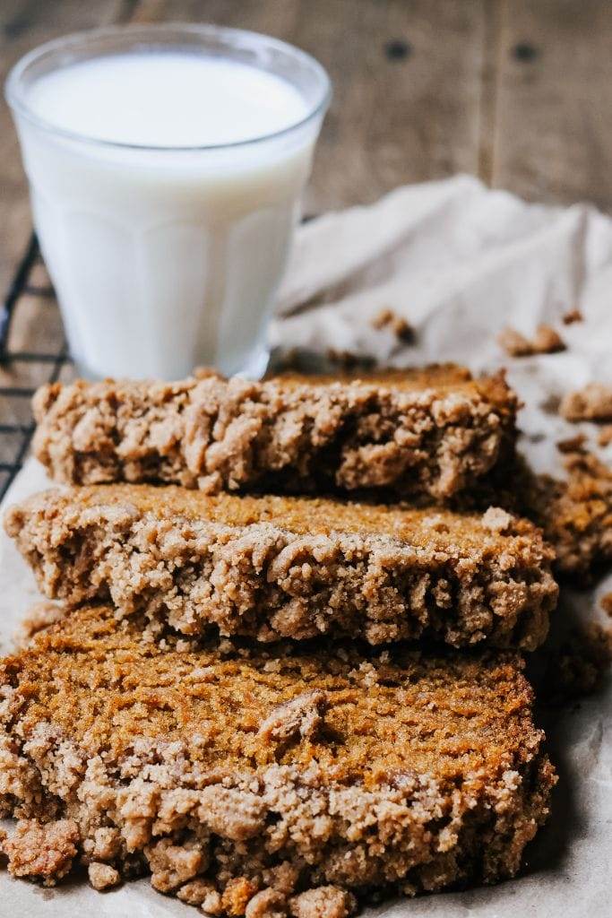 Several slices of pumpkin bread arranged on a cutting board, each topped with a golden-brown streusel and showing the moist crumb.