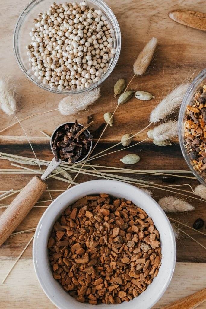 a bowl filled with peppercorns and a bowl filled with fall spices to make fall simmer pot recipes