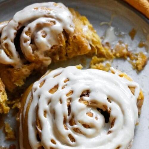 pumpkin cinnamon roll with cream cheese frosting on a plate