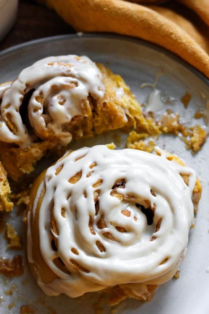 pumpkin cinnamon roll with cream cheese frosting on a plate