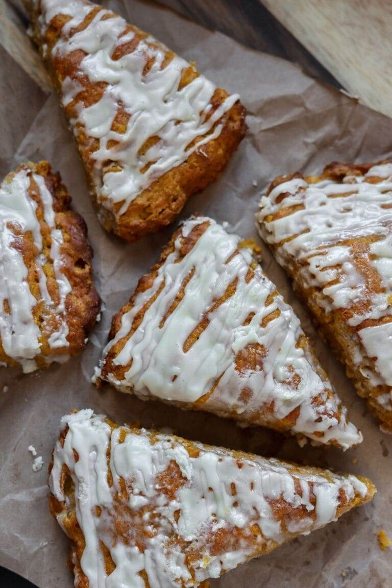 Close-up of a golden, flaky pumpkin scone with a smooth maple glaze.