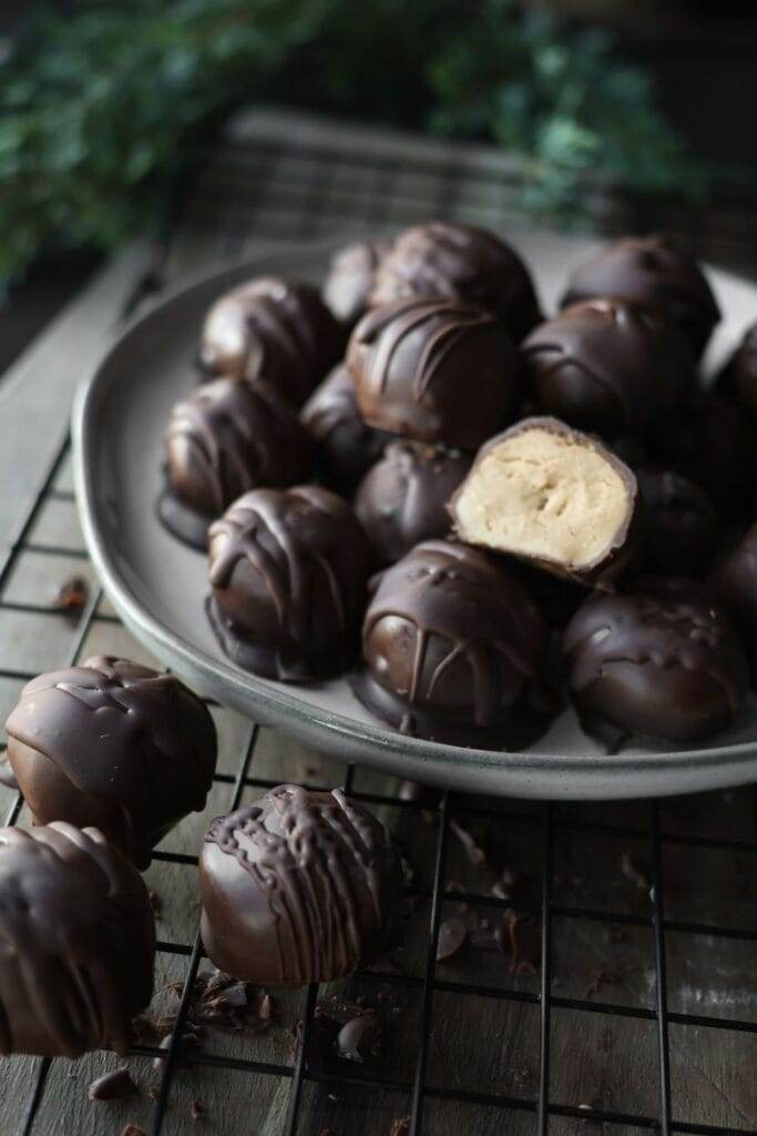 A batch of homemade chocolate peanut butter balls, chilled and set with a glossy chocolate coating.