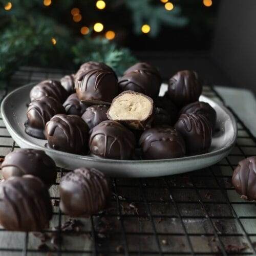 Chocolate-dipped peanut butter balls arranged on a baking sheet, drizzled with extra chocolate.