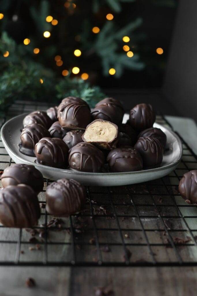 Chocolate-dipped peanut butter balls arranged on a baking sheet, drizzled with extra chocolate.