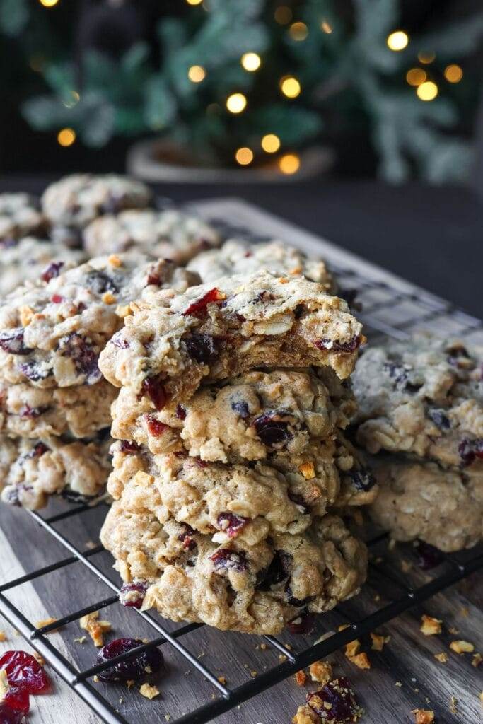 Freshly baked cranberry orange oatmeal cookies cooling on a wire rack, with a sprinkle of orange zest for garnish.