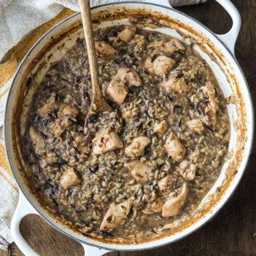 Finished Chicken and Wild Rice Skillet in a white enamel cast iron skillet, showcasing tender chicken, fluffy wild rice, and a creamy sauce.