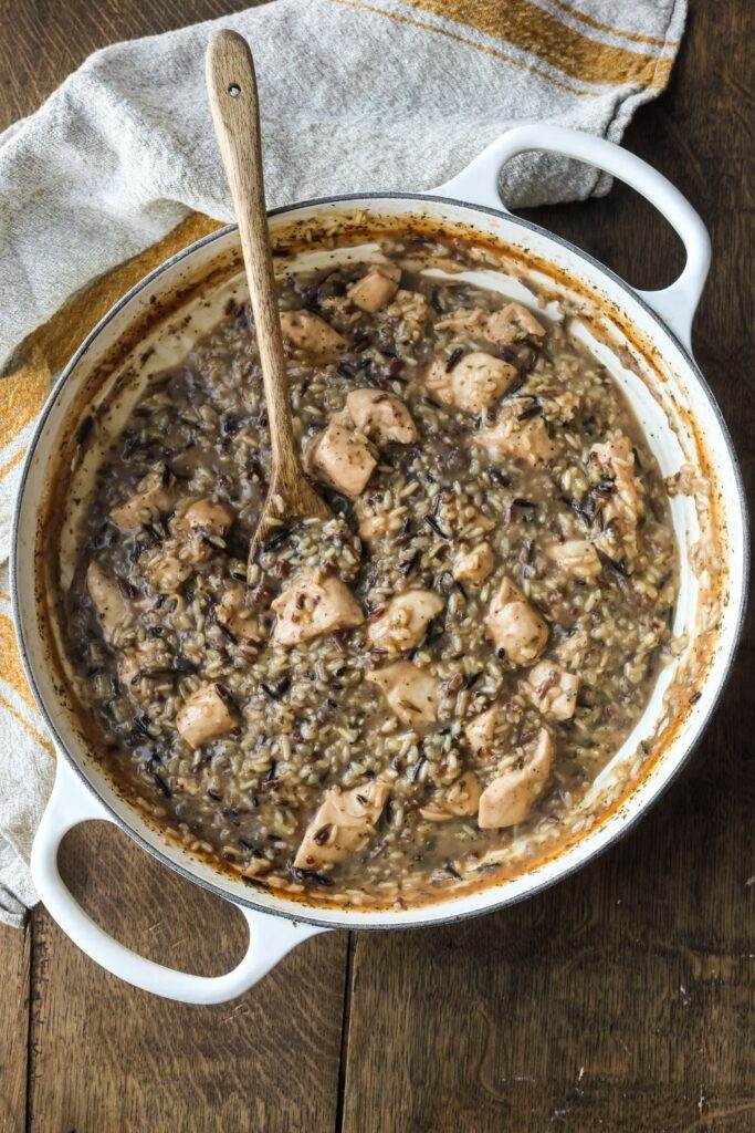 Finished Chicken and Wild Rice Skillet in a white enamel cast iron skillet, showcasing tender chicken, fluffy wild rice, and a creamy sauce.