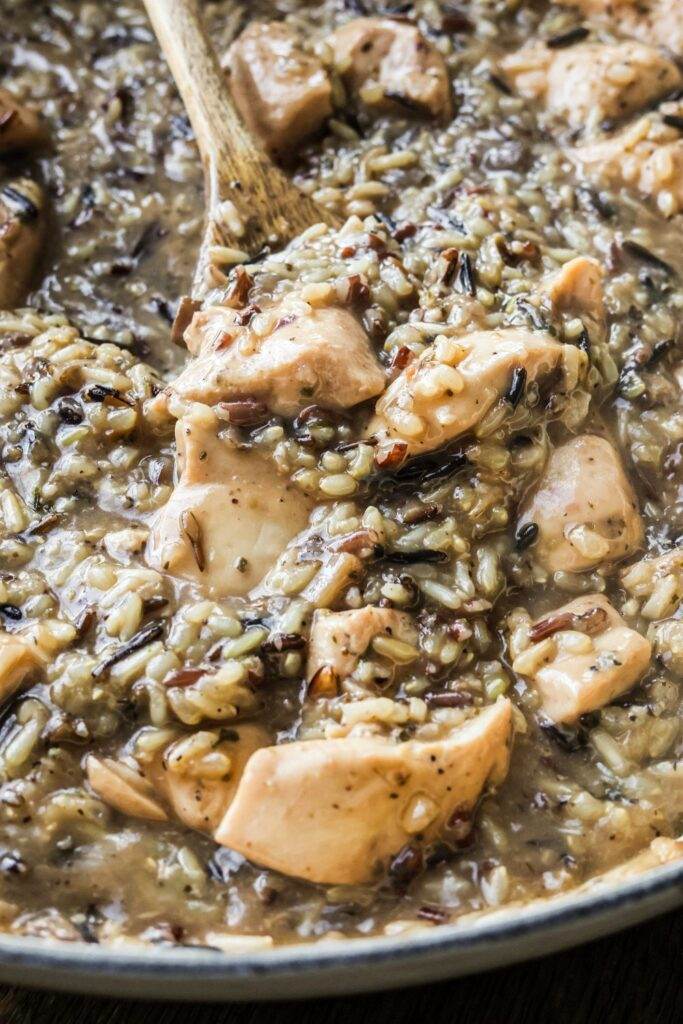 Close-up of the finished Chicken and Wild Rice Skillet, with a rich, creamy sauce, tender chicken, and nutty wild rice in a white enamel cast iron pan.