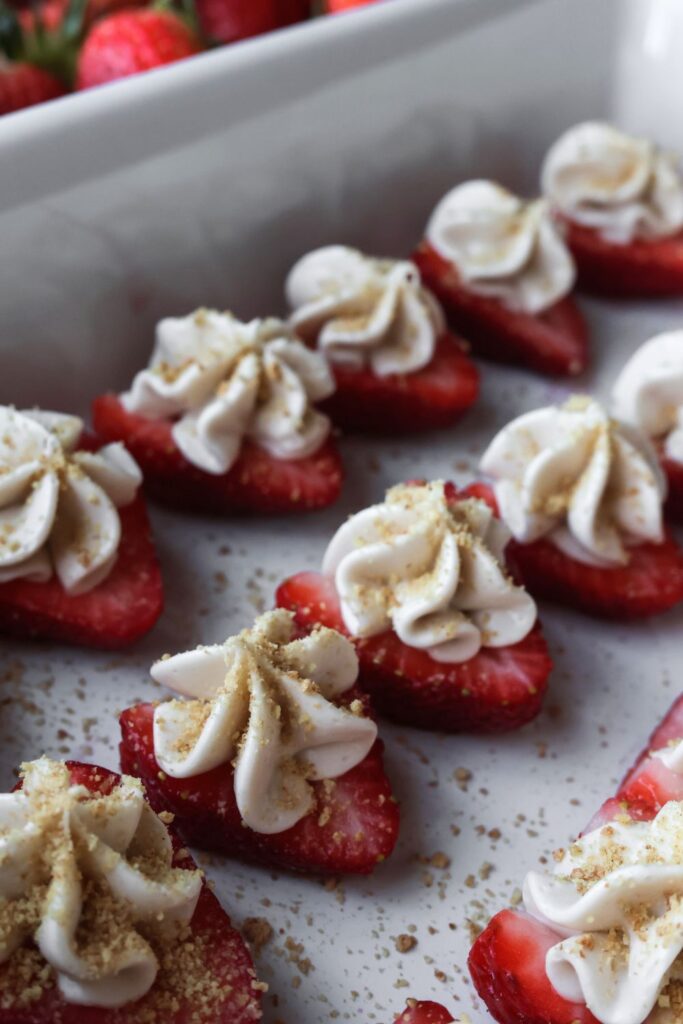 Close-up of a deviled strawberry, filled with cheesecake filling and sprinkled with graham cracker crumbs, showing its smooth and creamy texture.