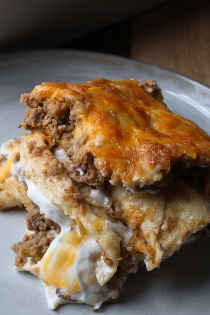 cose up of creamy burrito casserole with layers of tortillas, meat and beans and sour cream mixture