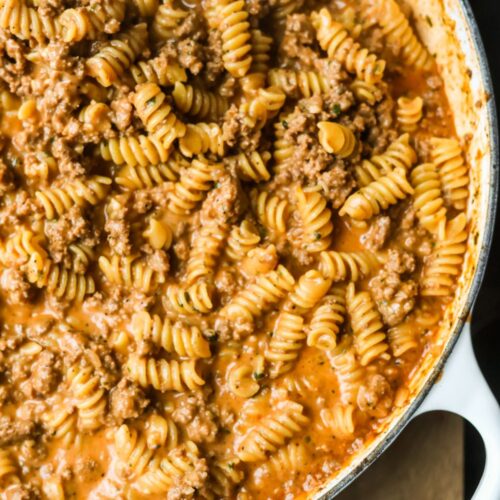 cheesy ground beef pasta in a white cast iron enamel skillet