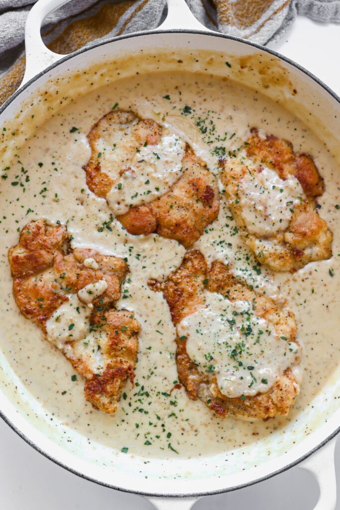 an overhead view of 4 thinly sliced chicken breast in a creamy white garlic sauce