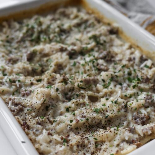 Homemade creamy hamburger rice casserole with ground beef, white rice, and a fresh parsley garnish.