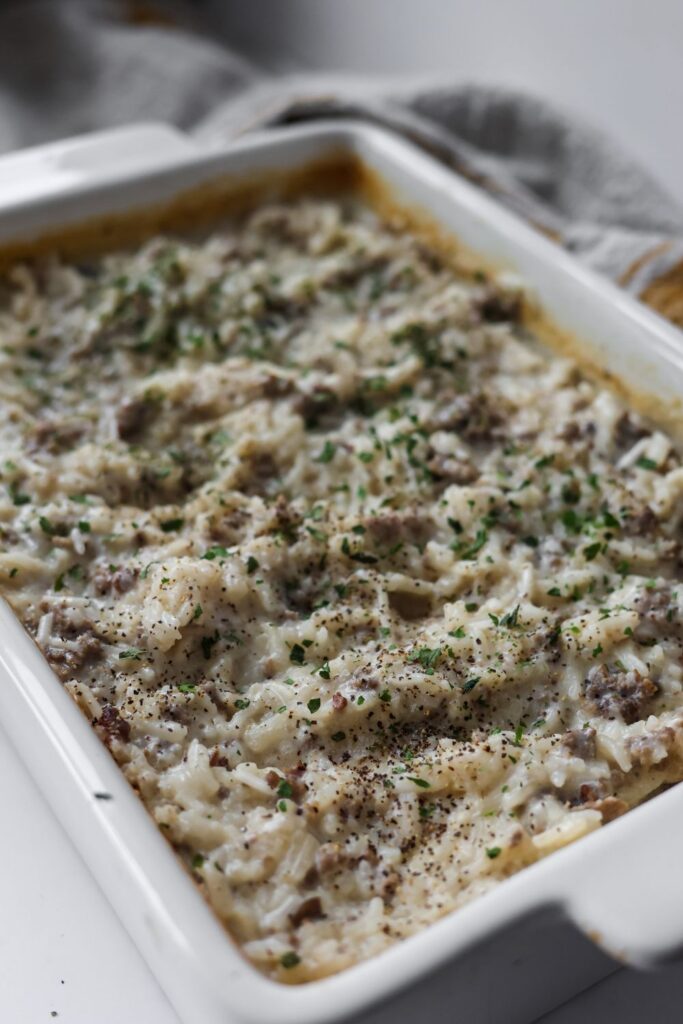 Homemade creamy hamburger rice casserole with ground beef, white rice, and a fresh parsley garnish.