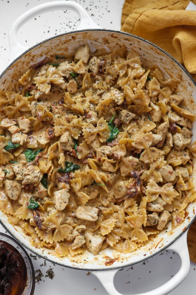 A delicious serving of Tuscan chicken pasta in a cast iron skillet, with creamy sauce, sun-dried tomatoes, and wilted spinach